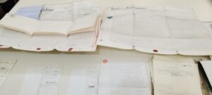 A set of old property deeds, handwritten in a typically floral style, displayed on a table
